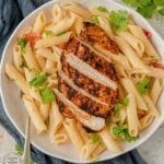 Blackened Chicken with dry rub spices charred on top of a bed of penne pasta in a bowl with olive oil, parmesan cheese and tomatoes #blackenedchicken #cajunchicken