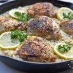 Large cast iron skillet chicken thighs lemon pepper risotto garnished with lemons