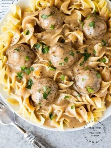 overshead shot swedish meatballs over large egg noodles in white bowl