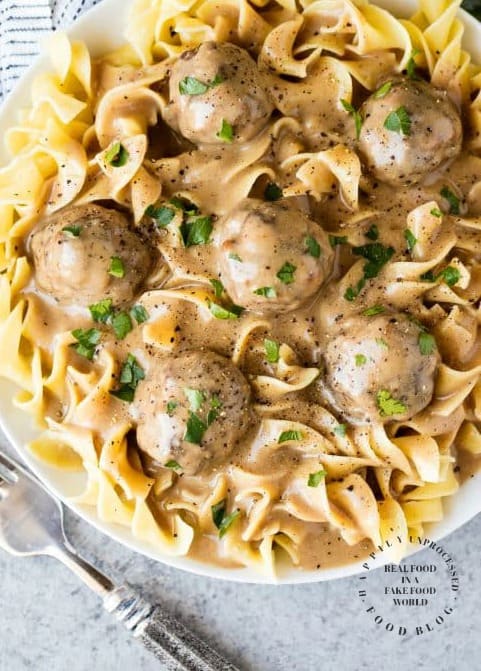 overshead shot swedish meatballs over large egg noodles in white bowl