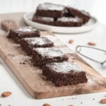 Healthy chocolate zucchini brownies with powdered sugar on top on cutting board