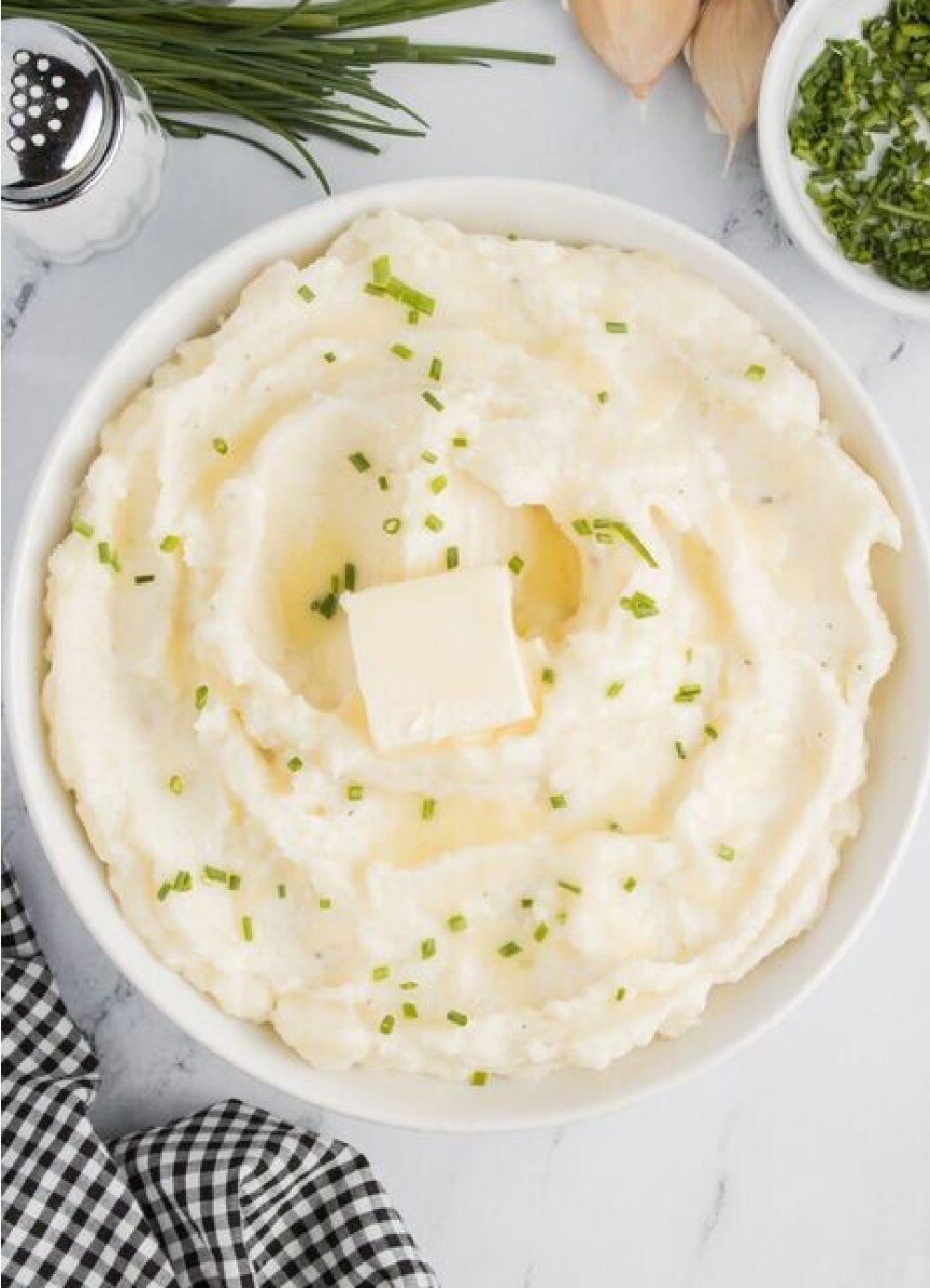 A bowl of creamy garlic mashed potatoes with fresh chives on top